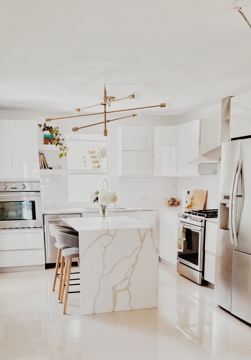 Photo by Rosana Solis A bright, modern kitchen featuring white cabinetry, stainless steel appliances, and minimalist decor.