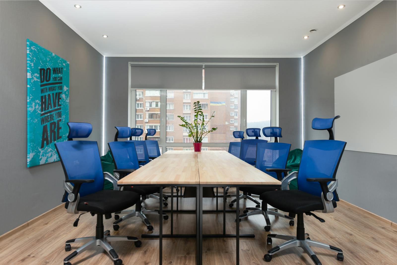 Photo by Max Vakhtbovycn Contemporary office space with blue chairs, table, and motivational quote on the wall.
