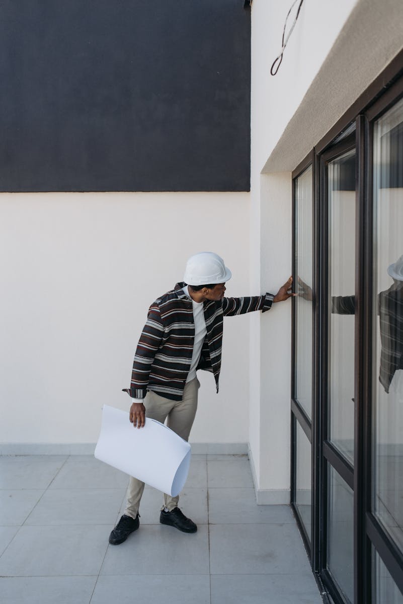 Photo by Pavel Danilyuk Architect examining building design with blueprint, focusing on modern architecture and construction details.